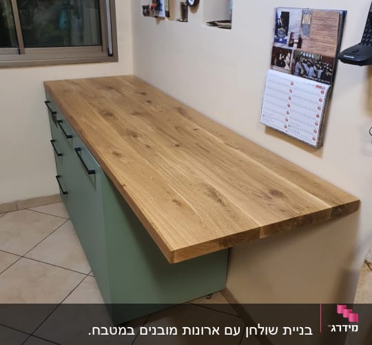 משטח עץ על ארון ירוק עם גלגלים